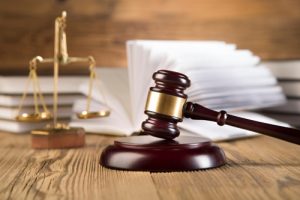 Golden scales of justice, gavel and books wood brown background